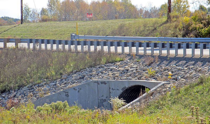 Side perspective of roadway over culvert with guardrail present